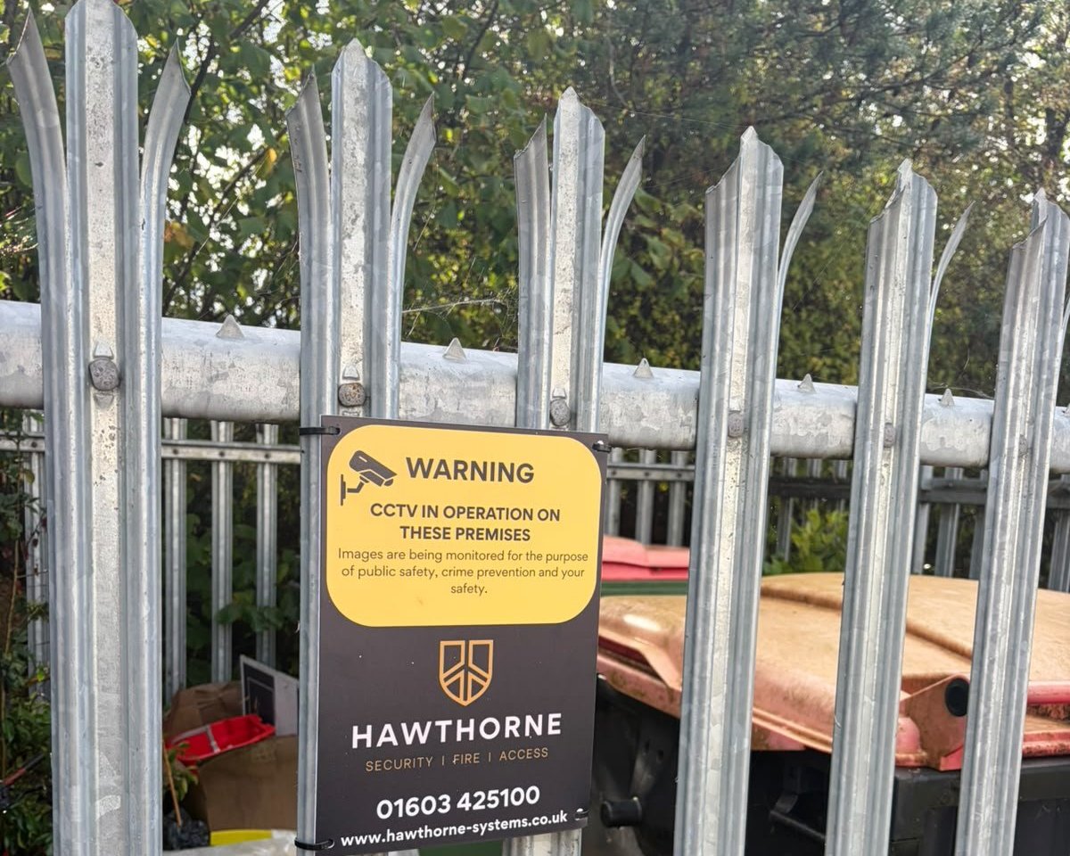 Hawthorne CCTV warning sign fixed to steel palisade fencing at a parish council site.